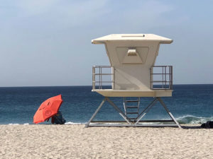 lifeguard tower next to an umbrella on the beach